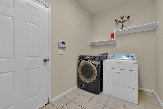 clothes washing area with laundry area, independent washer and dryer, light tile patterned flooring, and baseboards