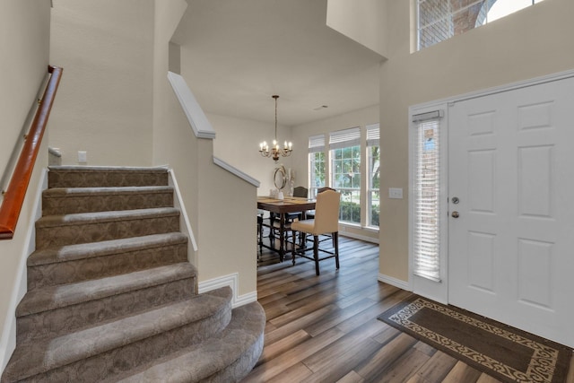 foyer with baseboards, a notable chandelier, stairway, and wood finished floors