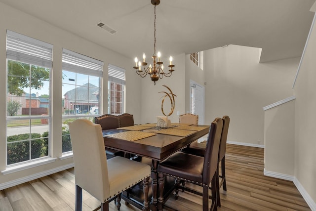 dining area featuring light wood-type flooring, plenty of natural light, and a notable chandelier