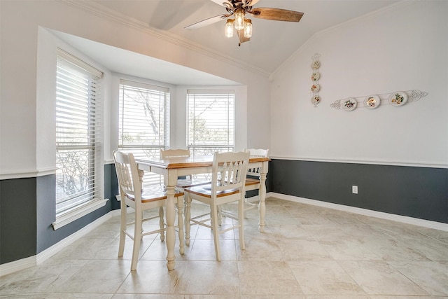 dining room featuring a ceiling fan, baseboards, vaulted ceiling, and crown molding