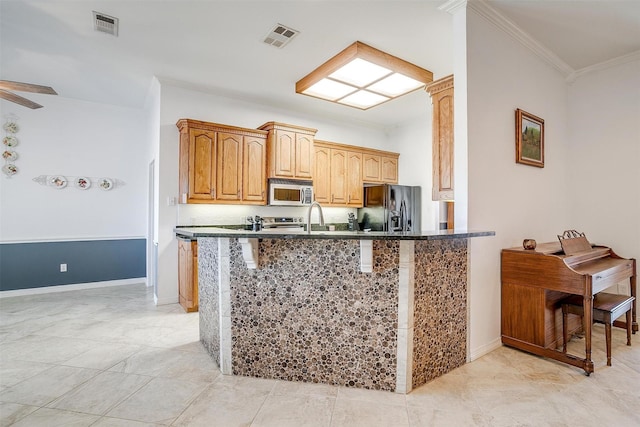 kitchen with stainless steel appliances, dark countertops, visible vents, and a peninsula