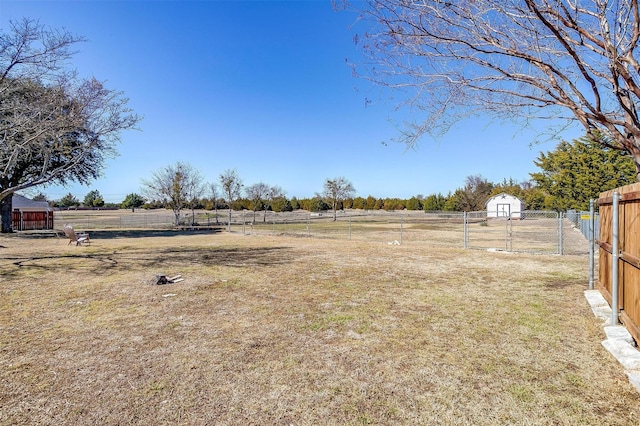 view of yard with a storage shed, a rural view, and fence