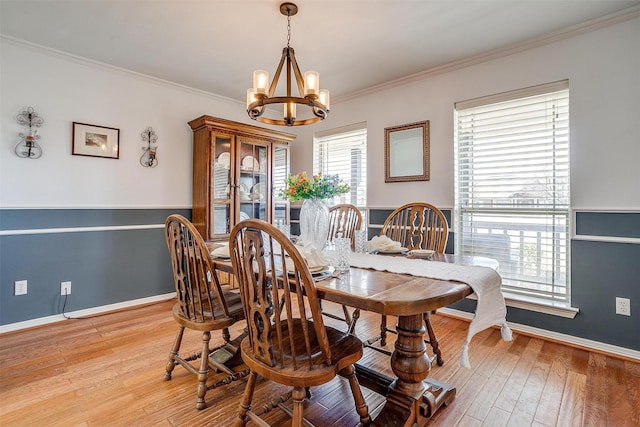 dining area featuring crown molding, light wood finished floors, a wealth of natural light, and an inviting chandelier