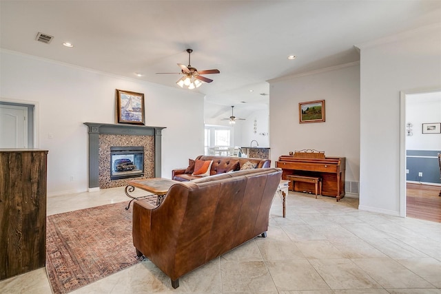 living room featuring light tile patterned floors, visible vents, baseboards, ornamental molding, and a tiled fireplace