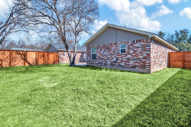 rear view of house featuring a lawn, brick siding, and a fenced backyard