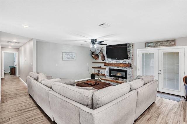 living room featuring visible vents, light wood-style flooring, baseboards, and ceiling fan