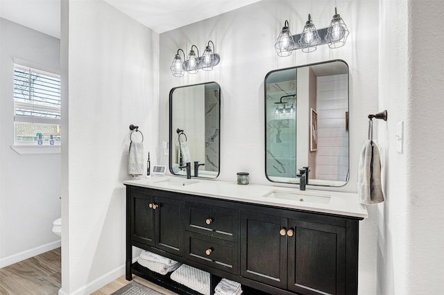 bathroom featuring double vanity, wood finished floors, baseboards, and a sink