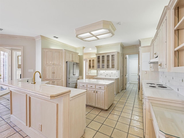 kitchen featuring a center island with sink, glass insert cabinets, freestanding refrigerator, light countertops, and under cabinet range hood