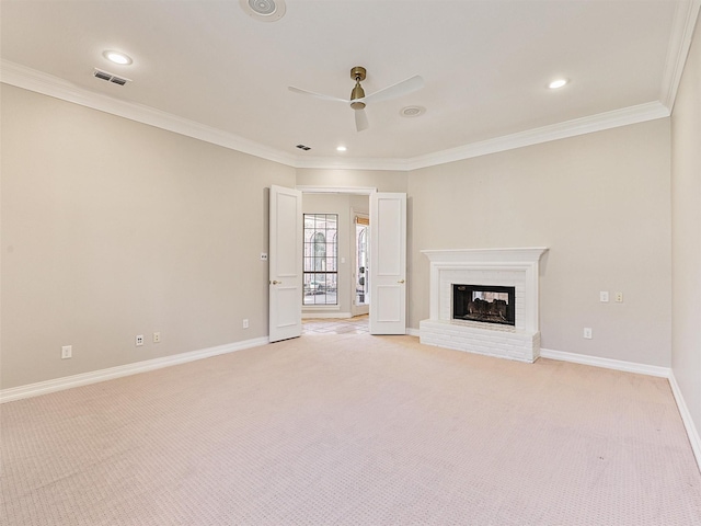 unfurnished living room featuring crown molding, light colored carpet, a brick fireplace, ceiling fan, and baseboards