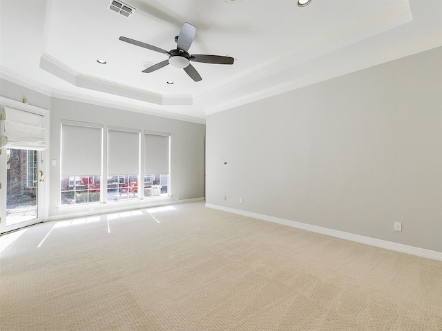 empty room with visible vents, baseboards, light colored carpet, ornamental molding, and a tray ceiling