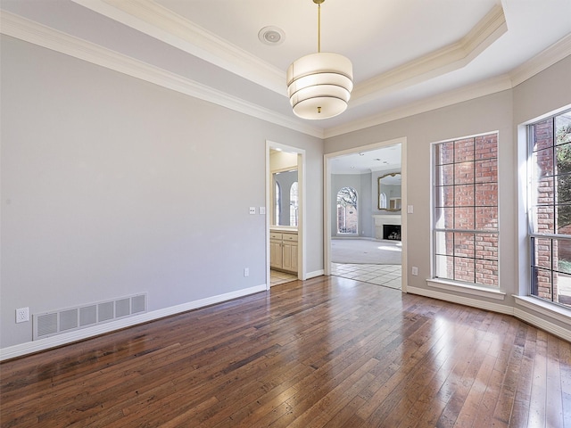 unfurnished room featuring visible vents, a raised ceiling, and dark wood-style flooring