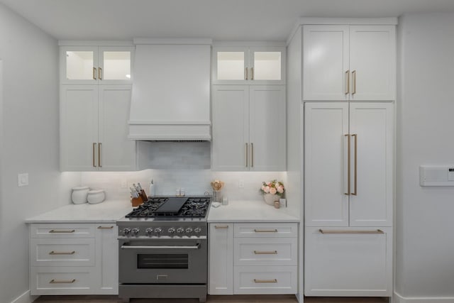 kitchen featuring glass insert cabinets, white cabinets, custom range hood, and high end stainless steel range