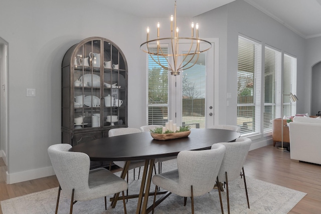 dining area with a chandelier, ornamental molding, wood finished floors, and baseboards