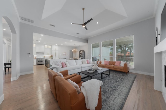 living area featuring light wood-type flooring, a fireplace, visible vents, and arched walkways