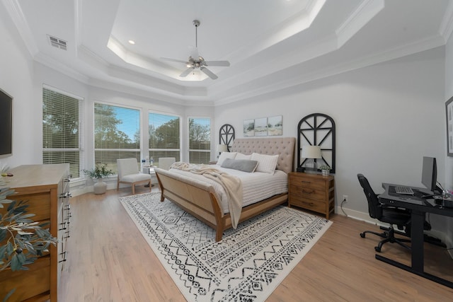 bedroom with ornamental molding, a tray ceiling, light wood-type flooring, and visible vents