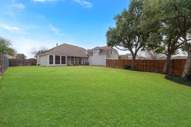 back of house featuring a fenced backyard and a lawn