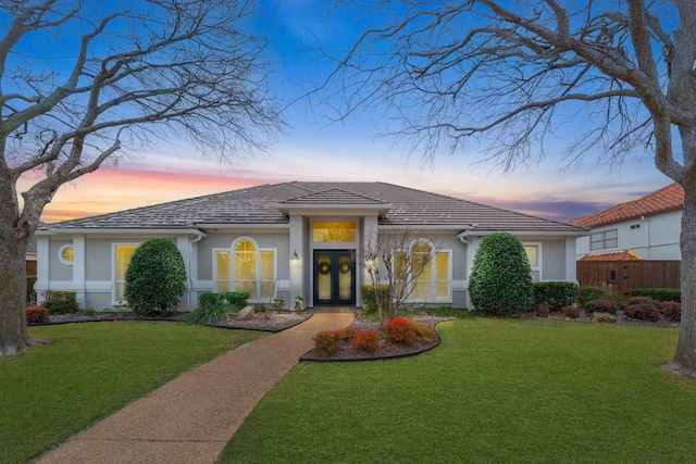 view of front facade featuring a yard, french doors, and stucco siding