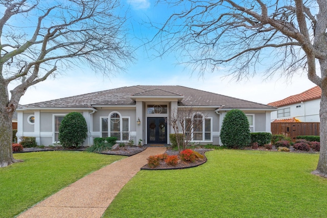 view of front of property with fence, a front lawn, and stucco siding