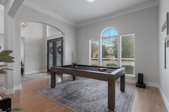 rec room with arched walkways, billiards, baseboards, ornamental molding, and light wood-type flooring