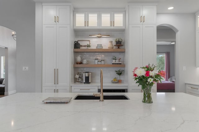 bar featuring arched walkways, a sink, and recessed lighting