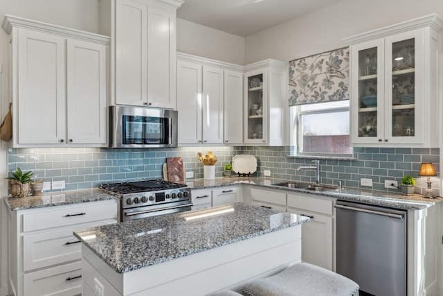 kitchen featuring white cabinetry, glass insert cabinets, stainless steel appliances, and a sink