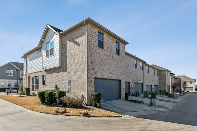 view of property exterior with a residential view, brick siding, driveway, and an attached garage