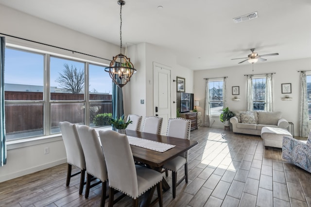 dining room featuring baseboards, visible vents, wood finished floors, and ceiling fan with notable chandelier