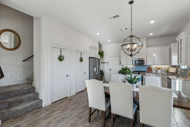 dining room with light wood-style floors, visible vents, stairs, and a chandelier