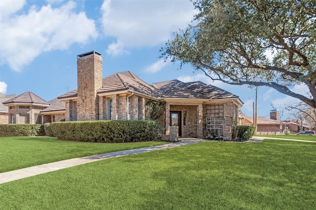 view of front of house featuring brick siding, a chimney, and a front yard