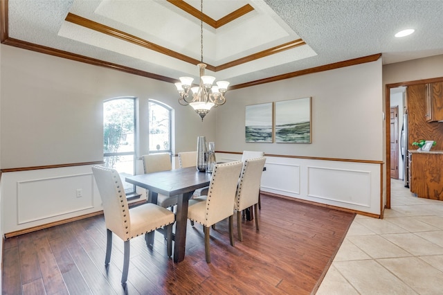 dining area with a textured ceiling, a tray ceiling, and crown molding