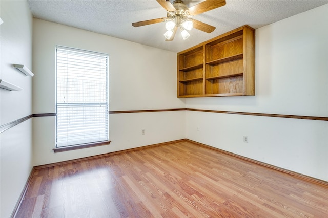 spare room with a textured ceiling, a ceiling fan, and light wood-style floors