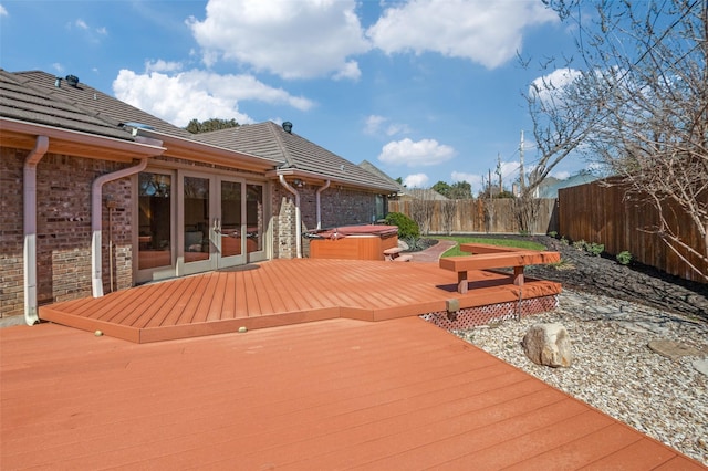 wooden deck with a hot tub, a fenced backyard, and french doors