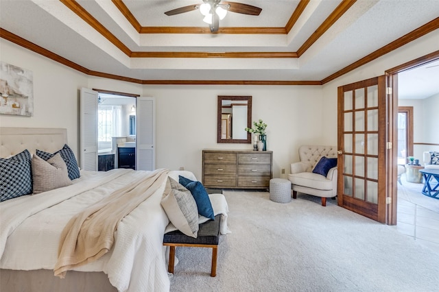 bedroom with a tray ceiling, ensuite bath, light colored carpet, and crown molding