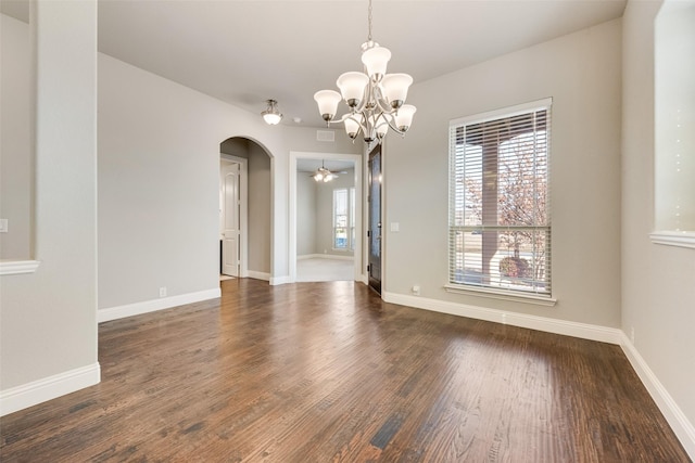 unfurnished room with arched walkways, wood finished floors, and baseboards