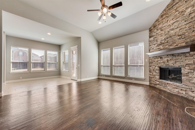 unfurnished living room featuring ceiling fan, a fireplace, wood finished floors, baseboards, and vaulted ceiling