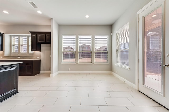 kitchen with light countertops, dark brown cabinets, visible vents, and baseboards