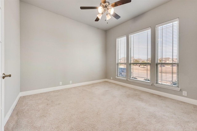 spare room with carpet, baseboards, and a ceiling fan