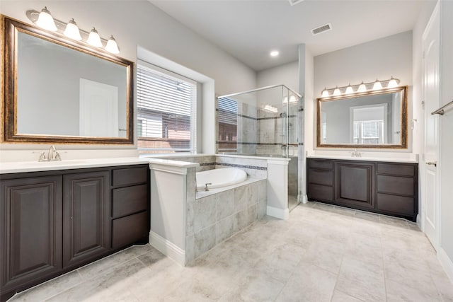 bathroom with visible vents, two vanities, a sink, a shower stall, and a bath