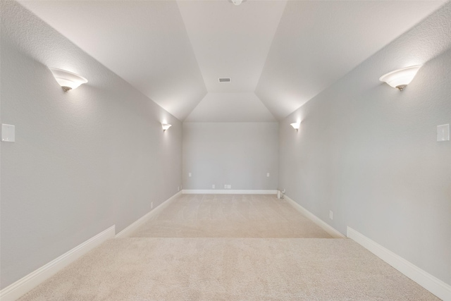 interior space with lofted ceiling, light carpet, visible vents, and baseboards