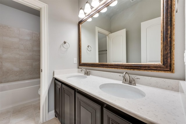 bathroom with double vanity, a sink, toilet, and tile patterned floors