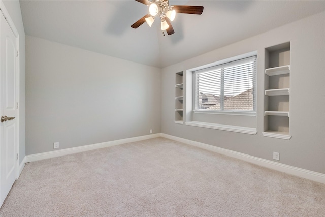 spare room featuring baseboards, ceiling fan, light colored carpet, and built in features