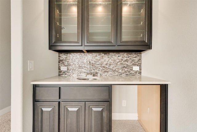 bar with tasteful backsplash, a sink, and baseboards