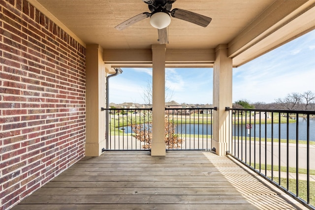 deck with a ceiling fan and a water view