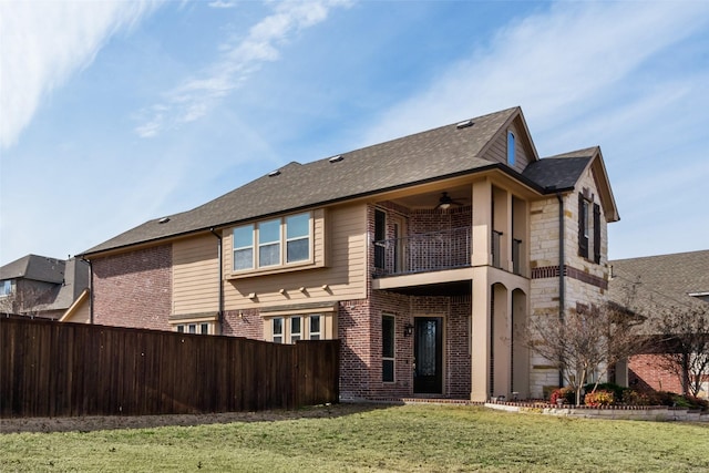 back of property with a balcony, brick siding, fence, a ceiling fan, and a yard