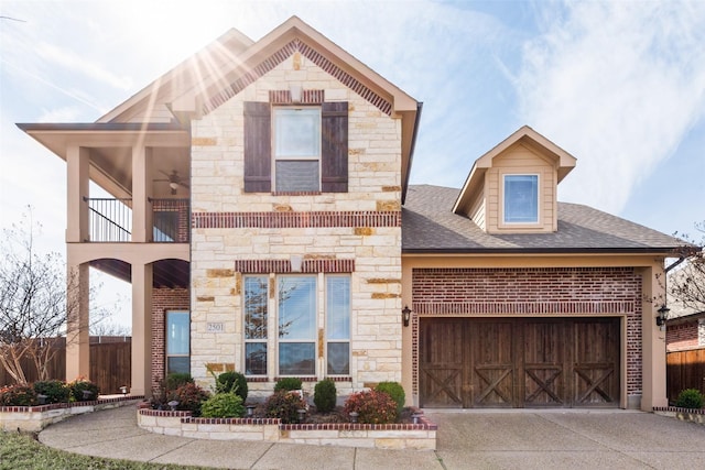 view of front of property featuring a garage, a shingled roof, concrete driveway, a balcony, and stone siding