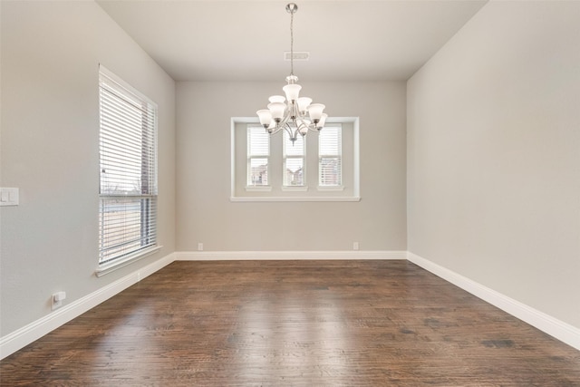 empty room featuring dark wood-style floors, visible vents, plenty of natural light, and a notable chandelier