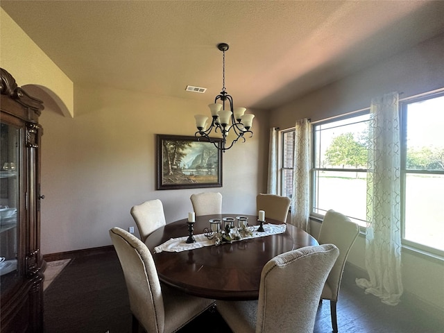 dining area featuring arched walkways, a notable chandelier, visible vents, baseboards, and dark wood finished floors