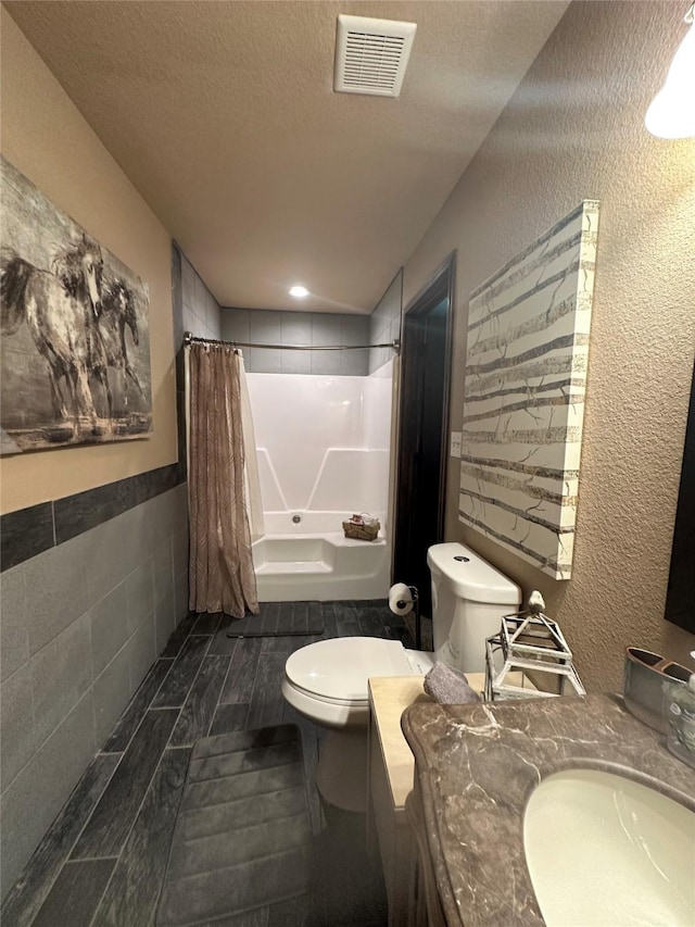 bathroom with a textured ceiling, toilet, shower / tub combo, vanity, and visible vents