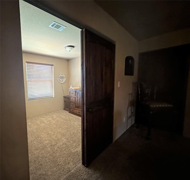 corridor featuring carpet floors, visible vents, and a textured ceiling