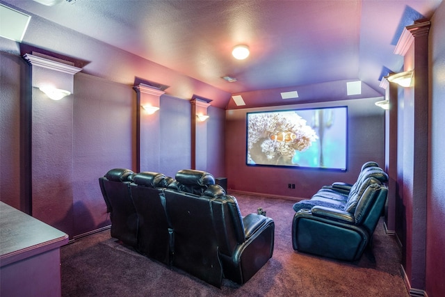 cinema with vaulted ceiling, dark colored carpet, and ornate columns